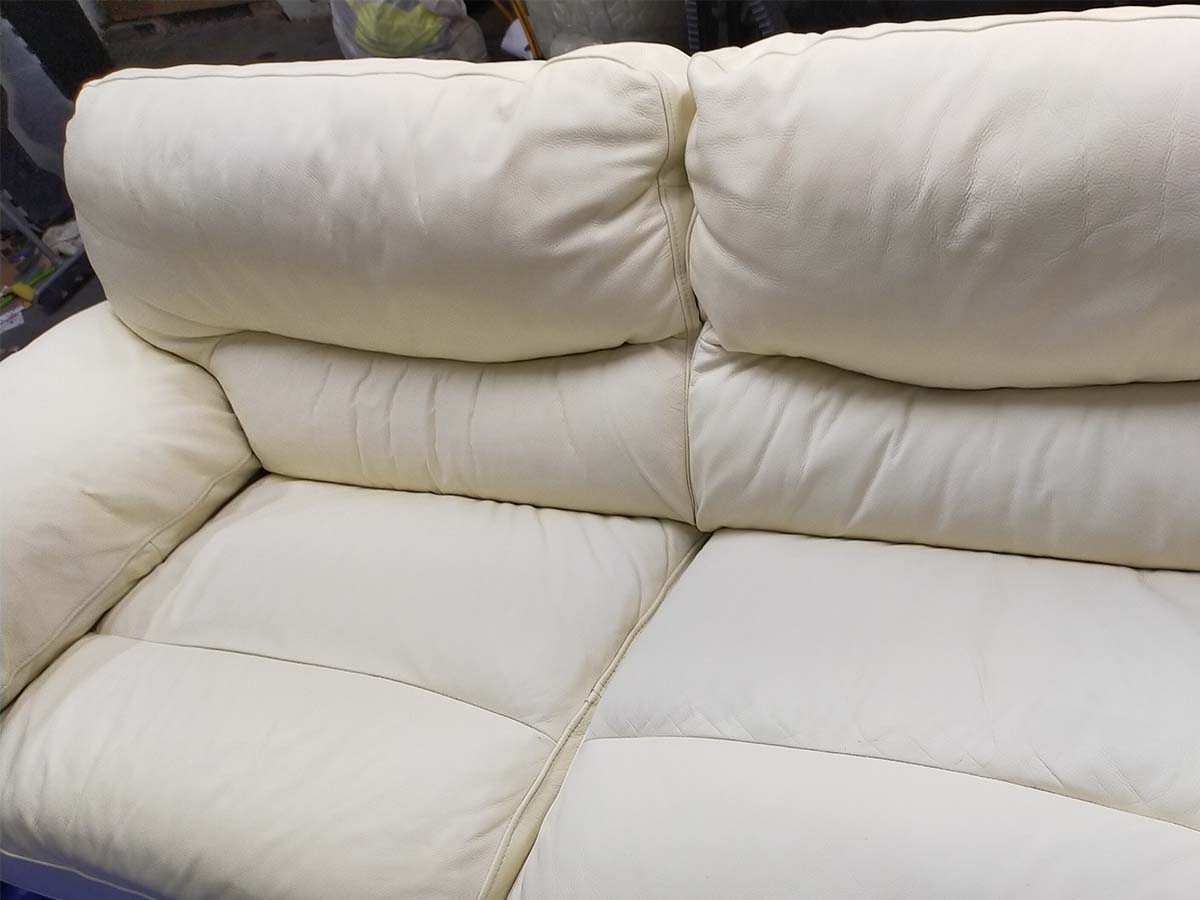 after image of a worn white leather sofa in need of repair